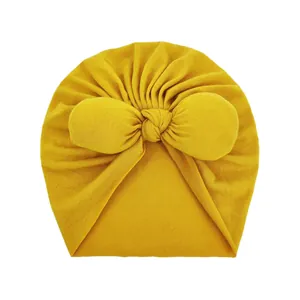Close-up of ginger yellow baby turban hat with oversized knit bow and ribbed texture