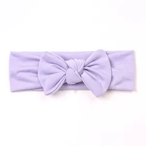 Detail of lavender ribbed knit baby headband with a large bow on a white background