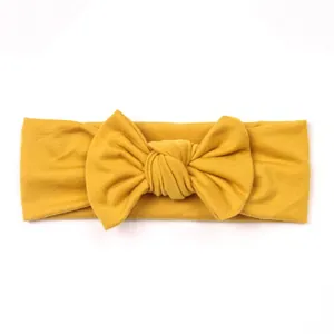 Close-up of mustard yellow knitted baby headband with a large decorative bow tie knot