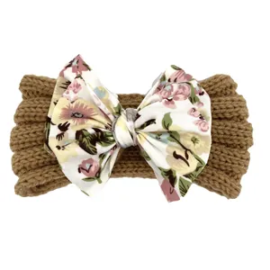 Détail d'un bandeau tricoté pour bébé avec un grand nœud à motif floral sur tissu brun