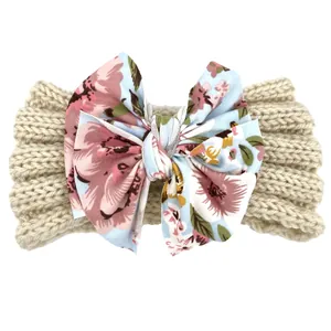 Gros plan d'un bandeau bébé en maille beige avec un grand nœud à motif floral