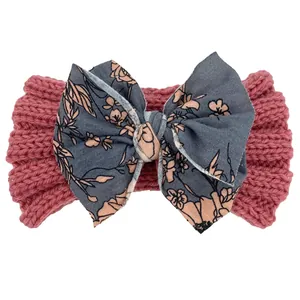 Détail du bandeau bébé avec bande en tricot rose et grand nœud à fleurs grises