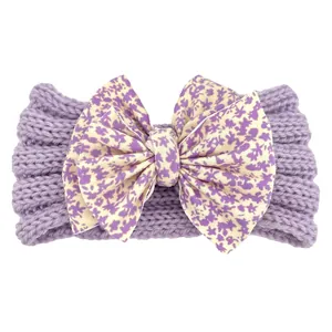 Détail d'un bandeau bébé en tricot violet orné d'un grand nœud à imprimé fleuri