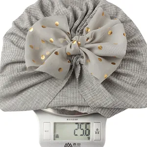 Detailed shot of grey ribbed baby turban showing a gold polka dot bow weighing 25.6g