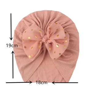 Detail of baby pink turban hat with ribbed texture and gold polka dot chiffon bow