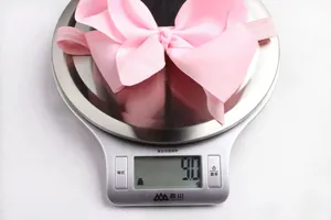 Macro detail showing a pink bow baby headband weighing 9.0g on a digital scale