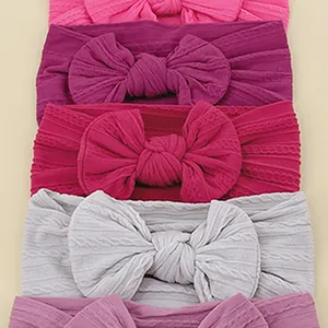 Set of five soft knit baby headbands with oversized bows in various pastel colors