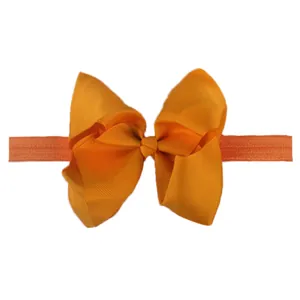 Detail of orange grosgrain ribbon bow on soft elastic baby headband with textured finish