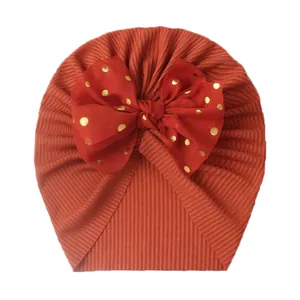 Infant ribbed turban hat in caramel with a red gold-dotted bow decoration