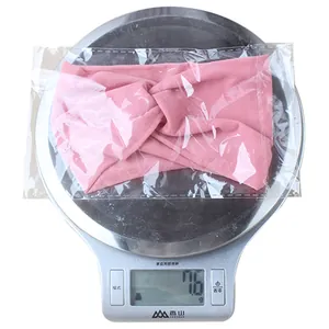 Pink nylon baby headband showing light weight of 7.6g on a digital scale measurement