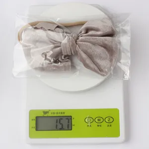 Gewichtsanzeige von 15,7g für das taupefarbene Samt-Babystirnband auf einer Waage