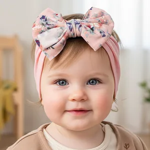 Gros plan d'un bandeau en nylon pour bébé avec un grand nœud à fleurs en tissu rose