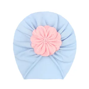 Turbante neonato azzurro con un grande fiore in tessuto rosa morbido sul davanti