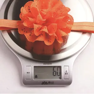 Gros plan du bandeau bébé à fleurs orange avec dentelle sur une balance numérique (6,0g)