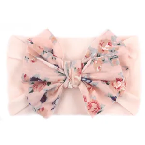 Détail d'un grand nœud à fleurs sur un bandeau de bébé en nylon rose clair