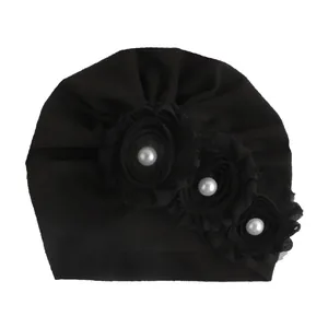 Dettaglio del turbante per neonati nero con fiori in chiffon e perle bianche