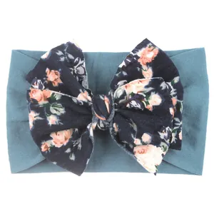 Détail d'un bandeau bébé en nylon sarcelle avec un grand nœud floral vintage et roses roses