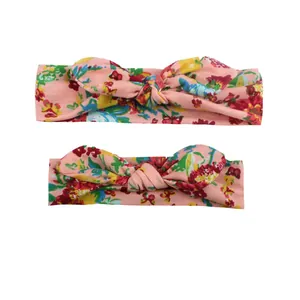 Detail of two floral print baby headbands with knotted rabbit ears on white background