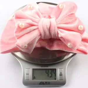 Pink velvet baby bow hat weighing 43.4g shown on a digital scale for precise detail