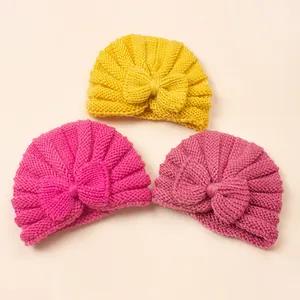 Close-up of knit baby hats with decorative bows in yellow, rose, and pink colors