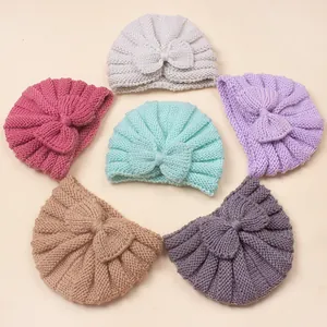 Flat lay of six colorful baby knit turban hats with decorative bows in a circle