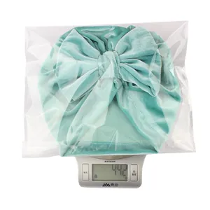 Mesure du poids de 44,2g pour le bonnet en velours à nœud bébé en emballage vert menthe