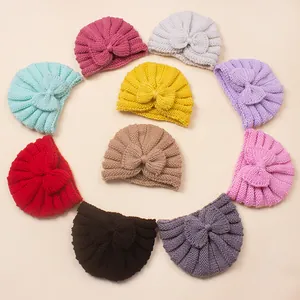 Flat lay of colorful knitted baby turban hats with bow detail in eleven vibrant color options