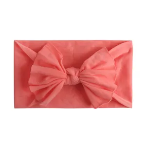 Macro-opname van de zachte nylon baby-hoofdband met koraalroze strik en gebreide textuur