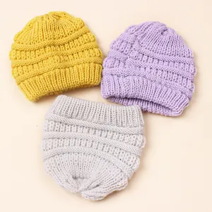 Detailed close-up of ribbed knit texture on baby winter hats in yellow, purple, and grey