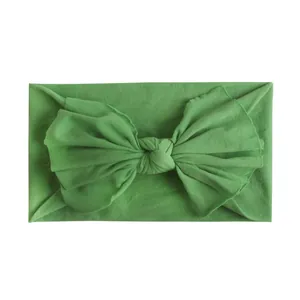 Detail van de grasgroene nylon textuur en grote strik op de zachte baby hoofdband