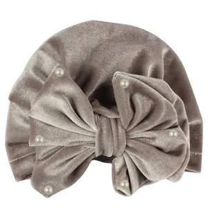 Detail of velvet baby turban with oversized bow and pearl accents in dusty mauve