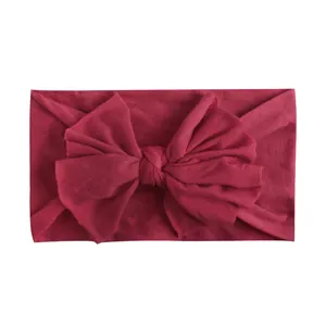Detail van zachte nylon baby hoofdband met bordeauxrode strik en gebreide textuur
