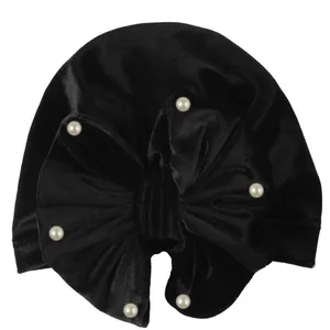 Detail of black velvet baby turban hat featuring a large bow and six white pearls