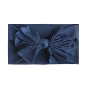 Close-up van een zachte marineblauwe nylon hoofdband met een grote strik voor baby's