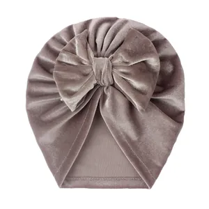 Détail du bonnet turban pour bébé en velours avec un grand nœud rose poudré