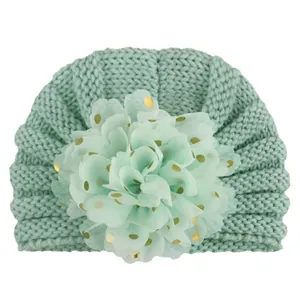Detail von mintgrüner Baby-Turban-Strickmütze mit großer Netzblume und Goldpunkten