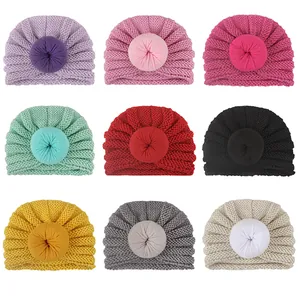 Dettaglio di nove berretti in maglia per neonati con pon-pon a forma di donut