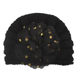 Detail der Baby-Turbanmütze mit schwarzem Strick und goldener gepunkteter Stoffblume