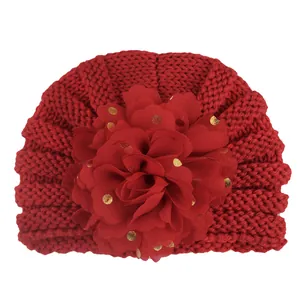 Detail der roten Baby-Turban-Mütze mit großer Chiffonblume und goldenen Punkten