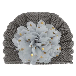 Detail der Strickstruktur einer dunkelgrauen Babymütze mit Goldpunkt-Blume