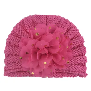 Detail einer rosafarbenen Baby-Strickmütze mit goldgepunkteter Mesh-Blume für Kleinkinder