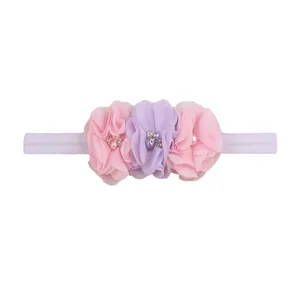 Detail of baby headband with three chiffon flowers, faux pearls and sparkling rhinestones
