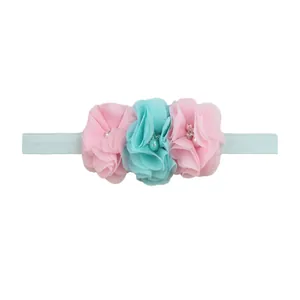 Detail of three chiffon flowers with pearls on an elastic baby headband for infants