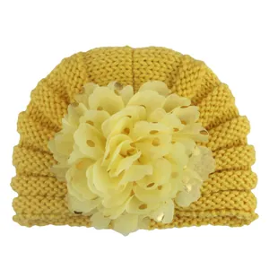 Detailaufnahme einer Baby-Strickmütze mit großer Chiffonblume und goldenem Punktdruck