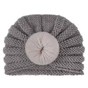 Dettaglio di cappello in maglia grigio per neonato con decoro a nodo rosa a ciambella
