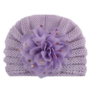 Detail der lavendelfarbenen Baby-Strickmütze mit Pailletten-Chiffonblume und Goldakzenten