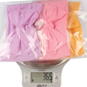 Three-pack nylon bow headbands in purple pink and yellow showing 36.5g weight on scale