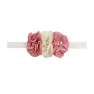 Detailed view of three chiffon flowers with pearls and crystals on an elastic baby headband