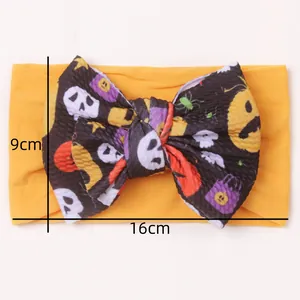 Detail view of large Halloween bow headband showing 16cm by 9cm dimensions on flat background