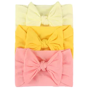 Close-up of three soft elastic nylon baby headbands with large bowknots in warm colors